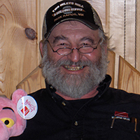 Staff member Nick poses for head shot with a pink panther plush.